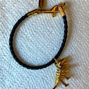 Black and gold Coach bracelet with Rexy dinosaur charm.